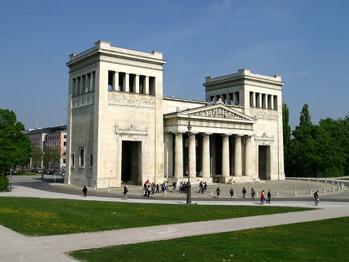 The Die Propylaeen, a historic white building at Koenigsplatz in Munich with people walking in front of it.