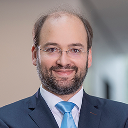 Headshot of Prof. Dr. Michael Stich, a middle age man smiling on a simple background.