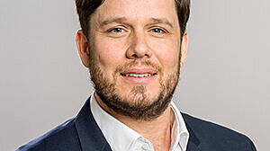Headshot of Prof. Dr. Andreas Pondorfer, a middle aged man smiling on a simple gray background.