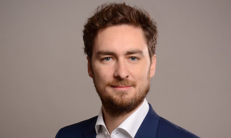 Headshot of Professor Philipp Lergetporer, a young man smiling on a simple grey background.
