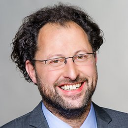 Headshot of Prof. Dr. Johannes Sauere , a middle age man smiling on a simple grey background.
