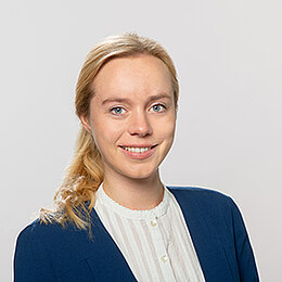 Headshot of Miriam Mahler, a young woman smiling on a simple light grey background.