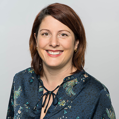 Headshot of Christina Green, a middle aged woman smiling at the camera on a simple light gray background.