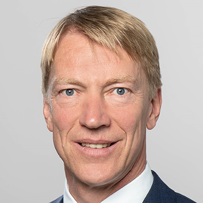 Headshot of Prof. Dr. Joachim Henkel, a man of mature age smiling on a simple gray background.